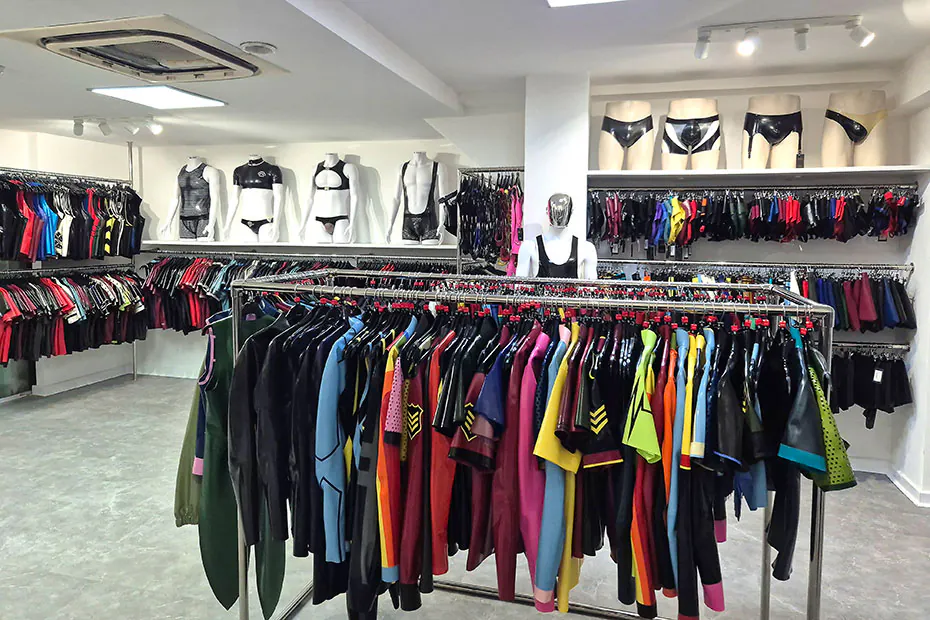 The men's floor: a long rail of latex shirts and trousers in green, blue, orange, red and yellow, with harnesses and briefs displayed on mannequins above.