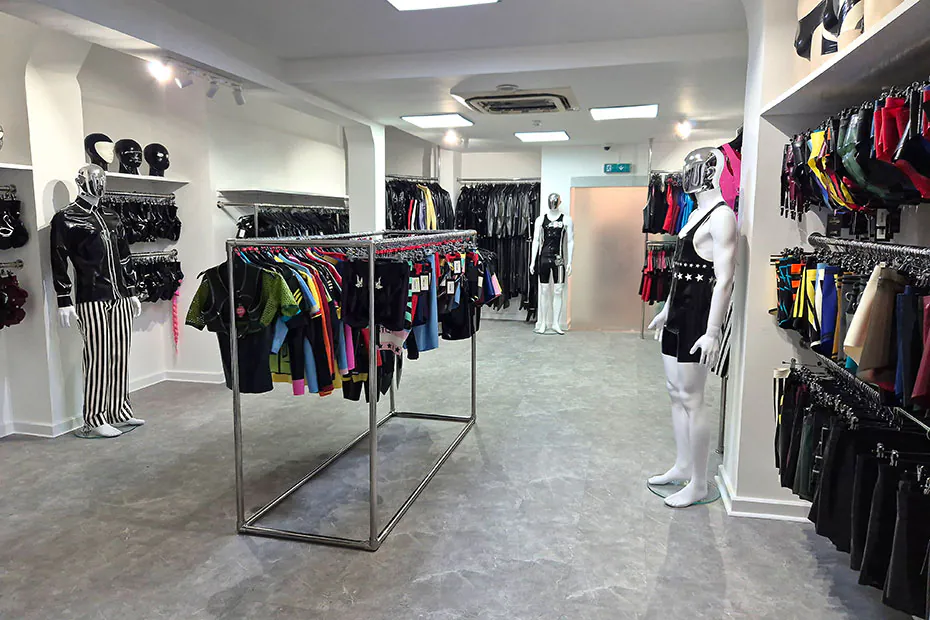 The men’s floor with mannequins in latex harnesses and striped latex trousers beside a chrome rail.