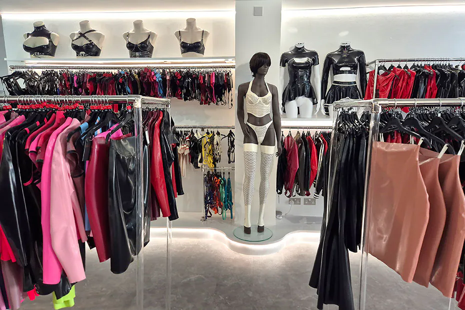 The women's floor: rails of latex dresses, skirts and tops in black, red, pink and nude, with corseted mannequins on a lit shelf above.